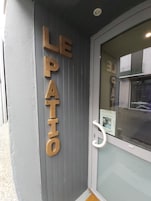 A door with the words "LE PATIO" in large letters, indicating a patio area.