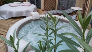 A spa area with a hot tub, two massage beds, and a seating area with a table and chairs. - Le Patio de Luchon (Bagneres-de-Luchon)
