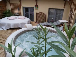 A spa area with a hot tub, two massage beds, and a seating area with a table and chairs.
