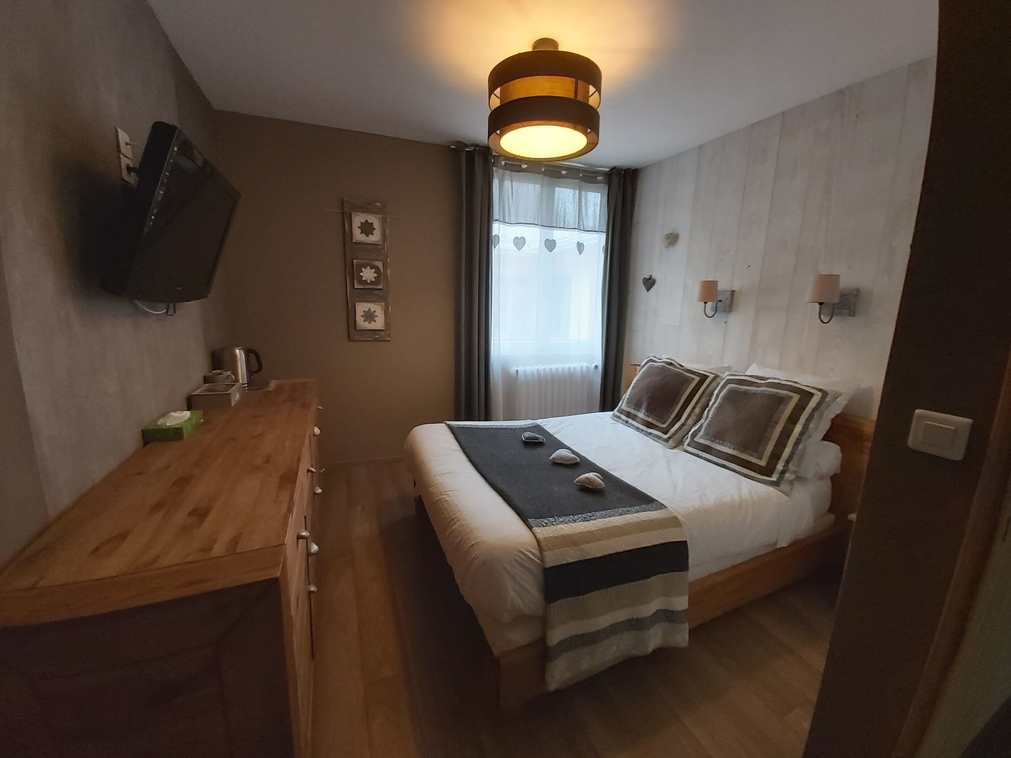 Una camera da letto con un letto, un comodino, una lampada e una TV a parete.