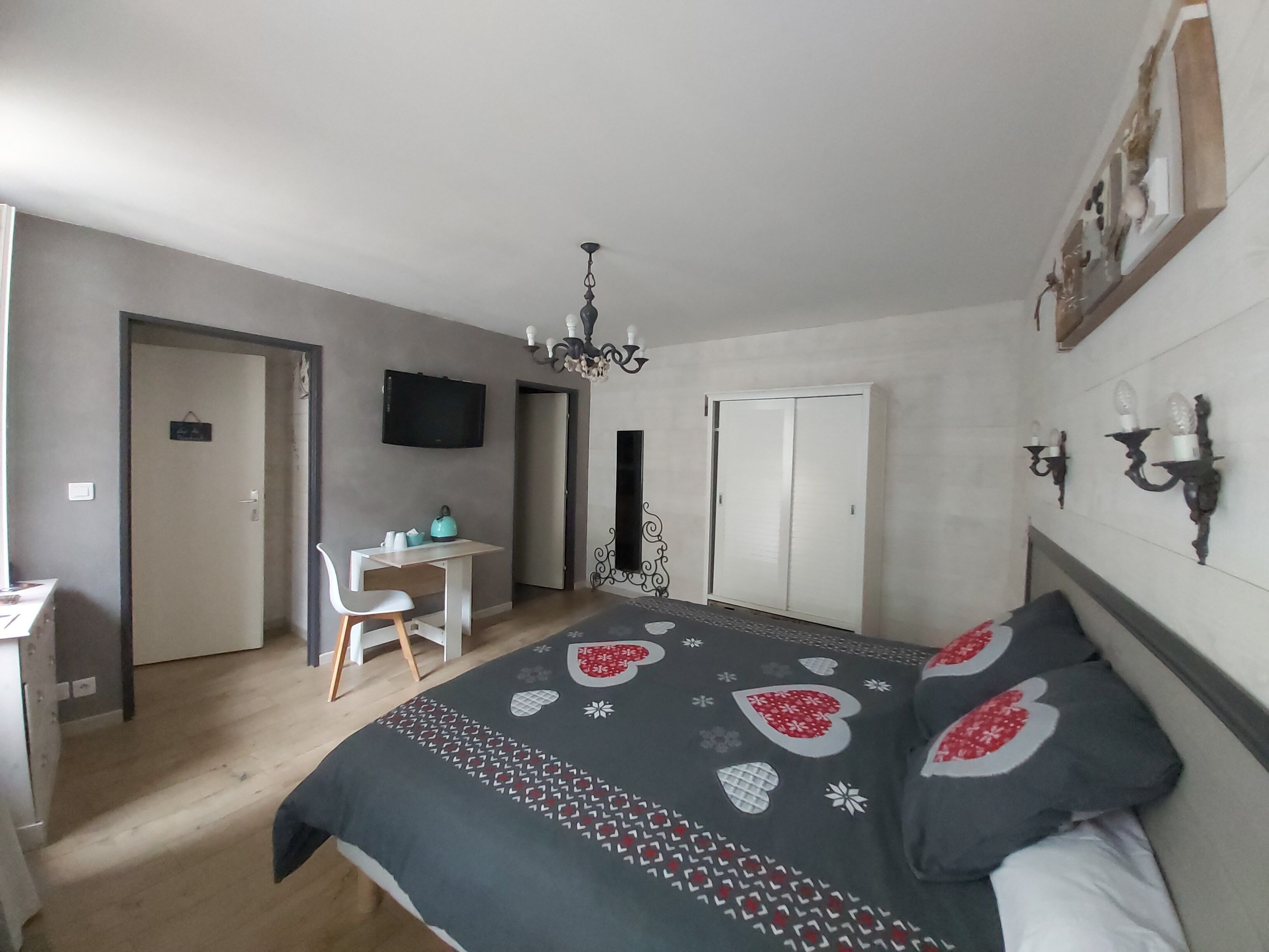 Un dormitorio con cama, escritorio, silla, televisor y armario.
