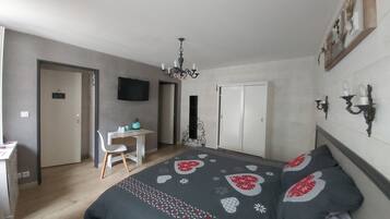Un dormitorio con cama, escritorio, silla, televisor y armario.