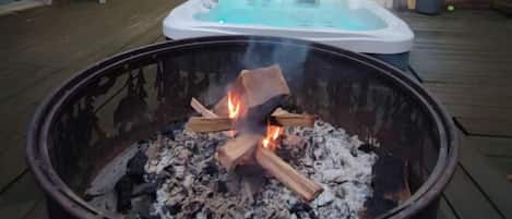 Ein Whirlpool auf einer Holzterrasse, im Vordergrund eine Feuerstelle.
