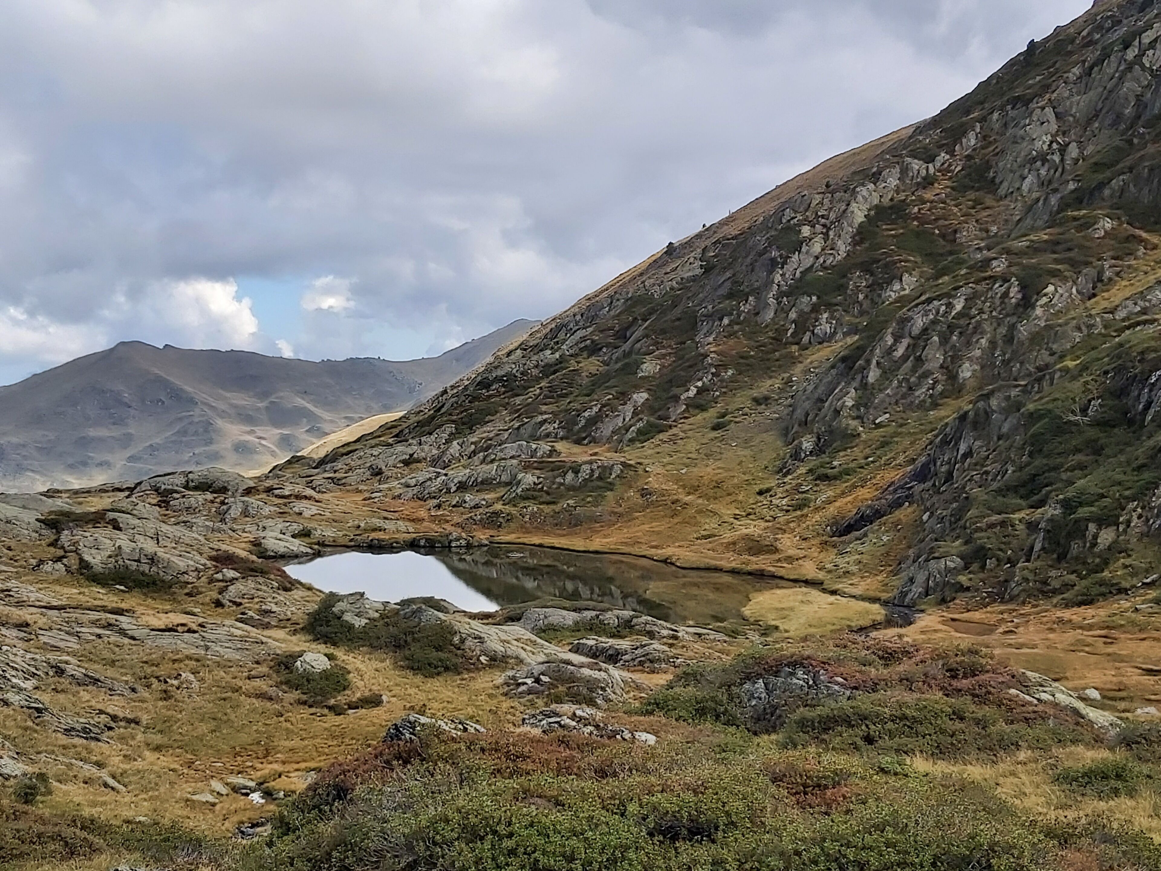 Un paysage montagneux avec un petit lac et un terrain rocheux.