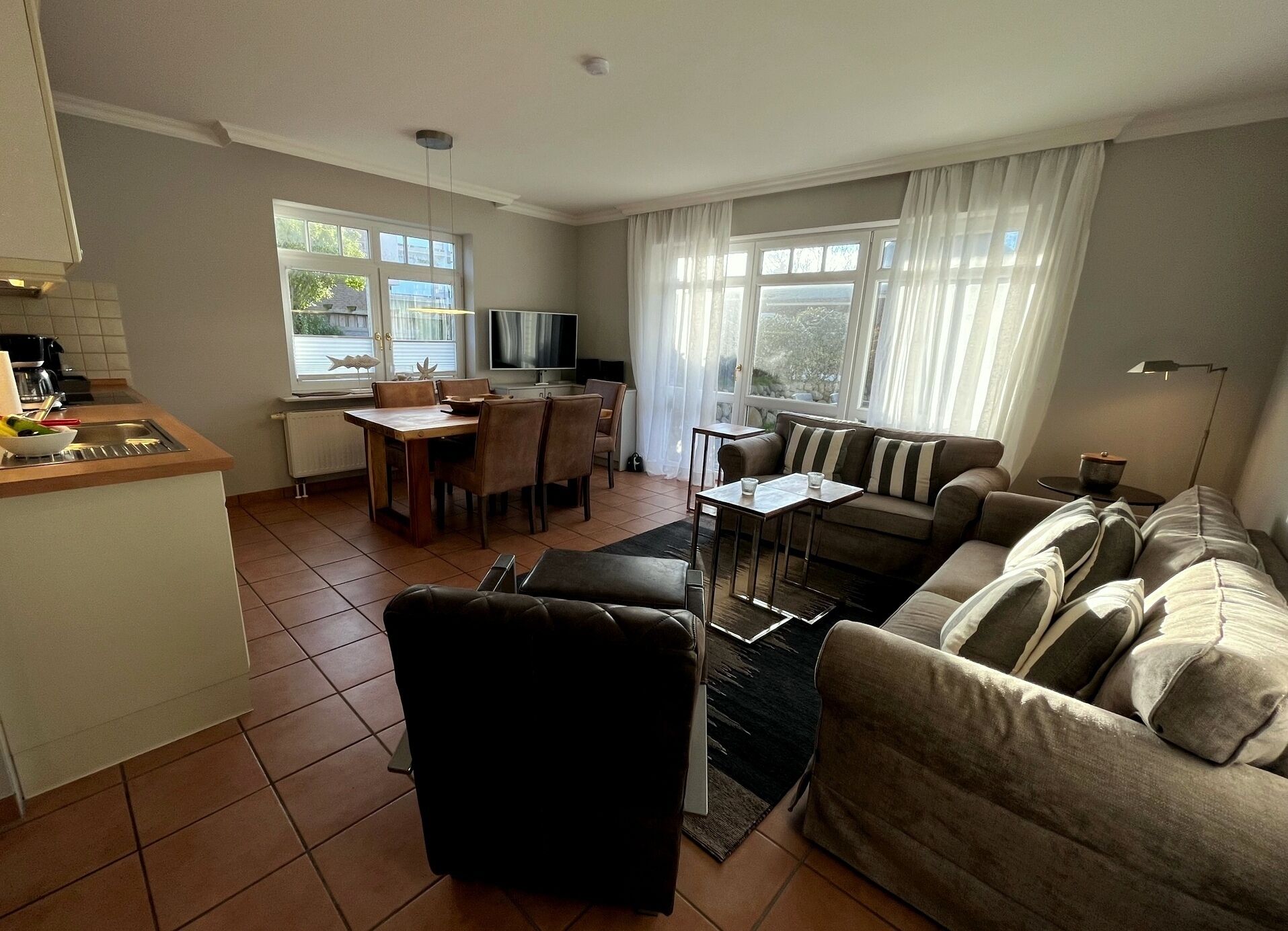 A modern living room with a sofa, a coffee table, and a dining area with chairs and a table.