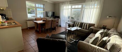 A modern living room with a sofa, a coffee table, and a dining area with chairs and a table.