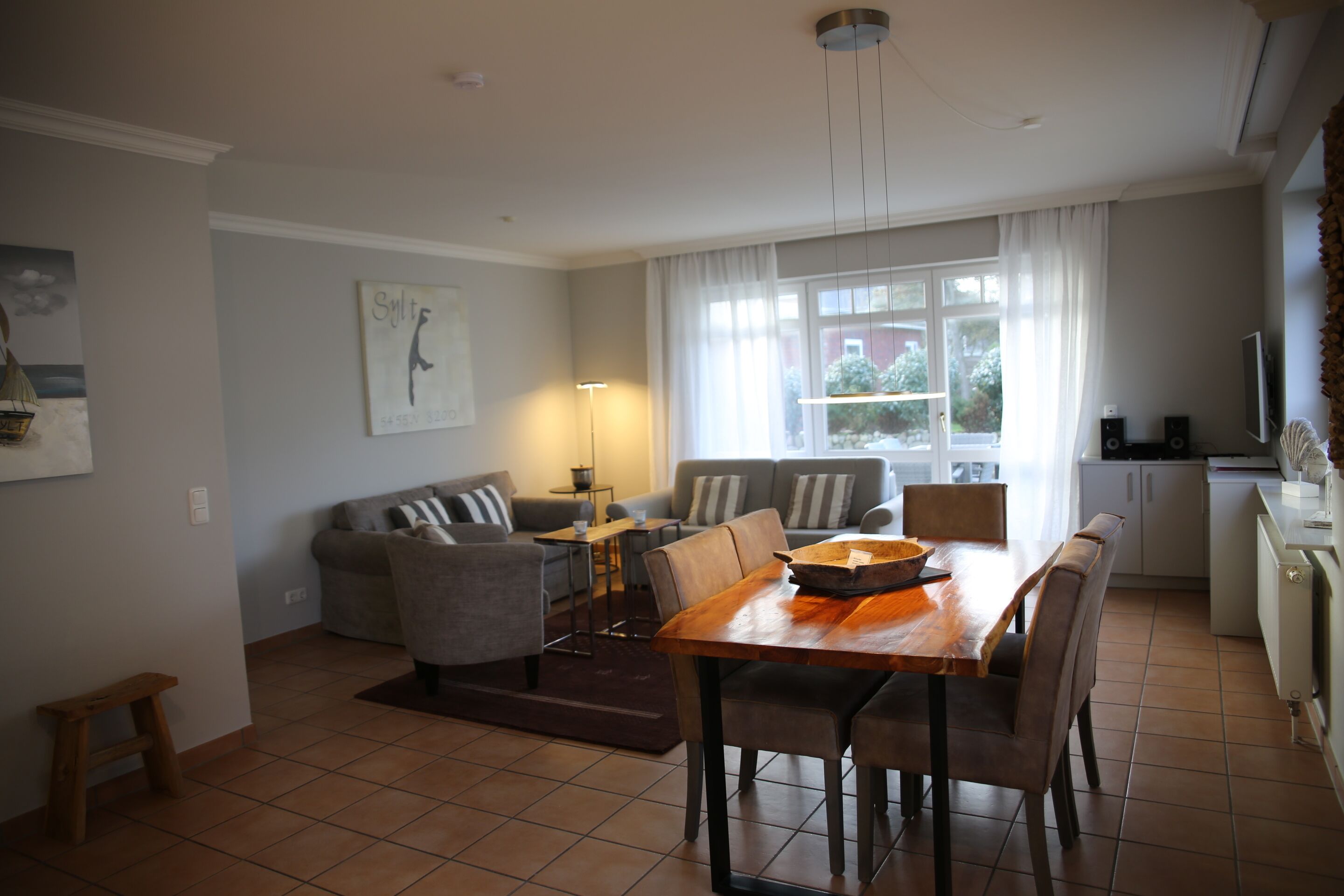 A modern living room with a dining area, a sofa set, a coffee table, and a kitchen in the background.