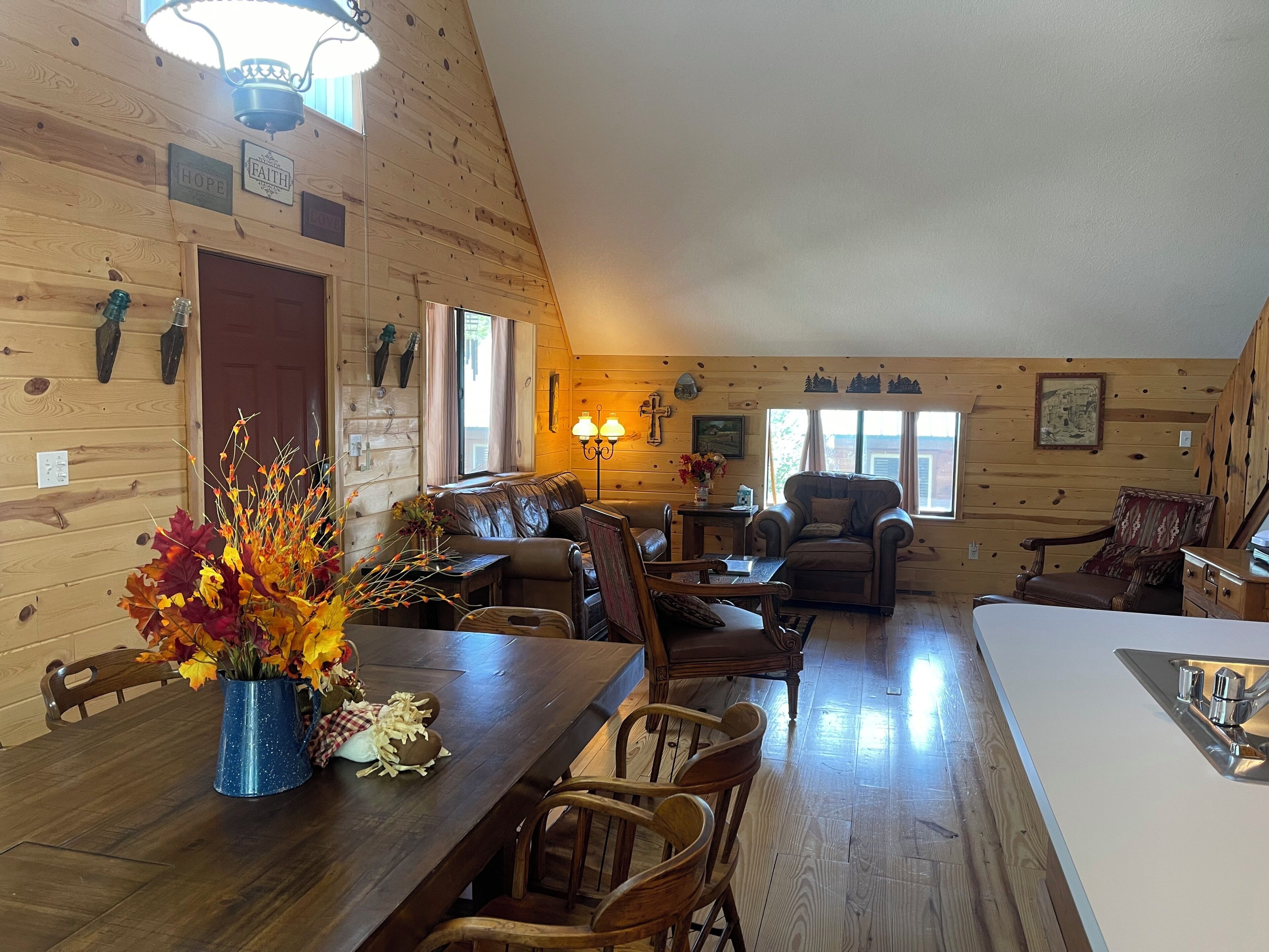 Un intérieur de chalet chaleureux comprenant un coin repas, un salon avec cheminée et un espace cuisine.