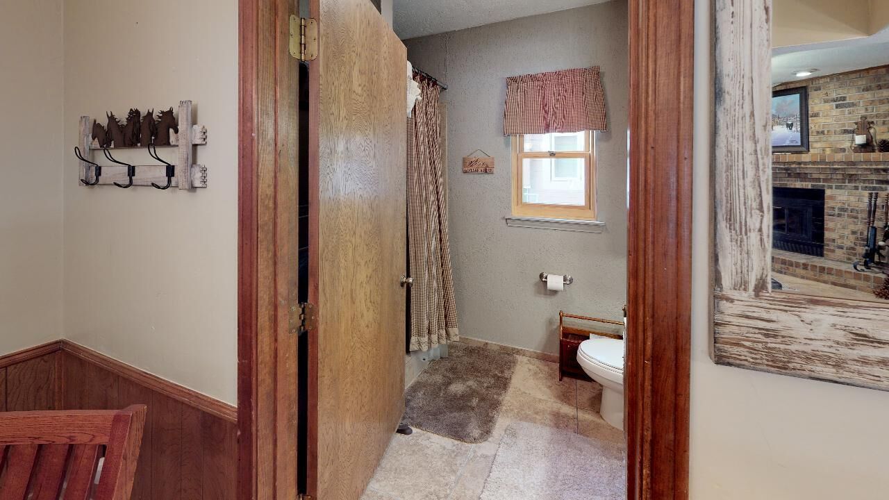 A bathroom with a shower, toilet, and a window.