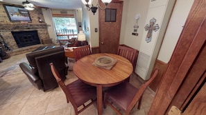 Un comedor con una mesa redonda de madera, sillas de cuero, una chimenea y vistas al exterior.