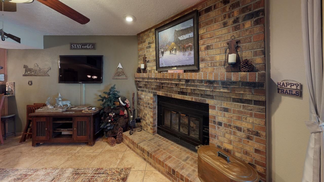 A living room with a fireplace, a television, and a Christmas tree.