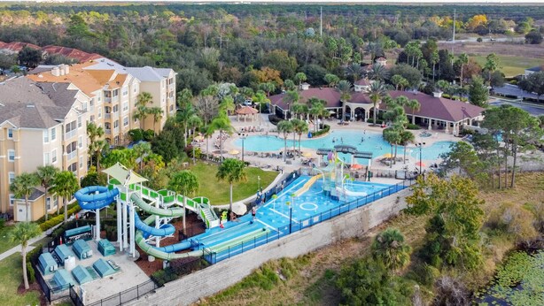 Un resort con varias piscinas, parque acuático y un edificio grande con balcones.