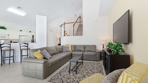 Una sala de estar moderna con un sofá modular, una mesa de centro y un televisor montado en la pared.