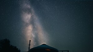 Un grande edificio a forma di cupola, con un ingresso ben visibile e una struttura sulla sommità, sullo sfondo di un cielo stellato.