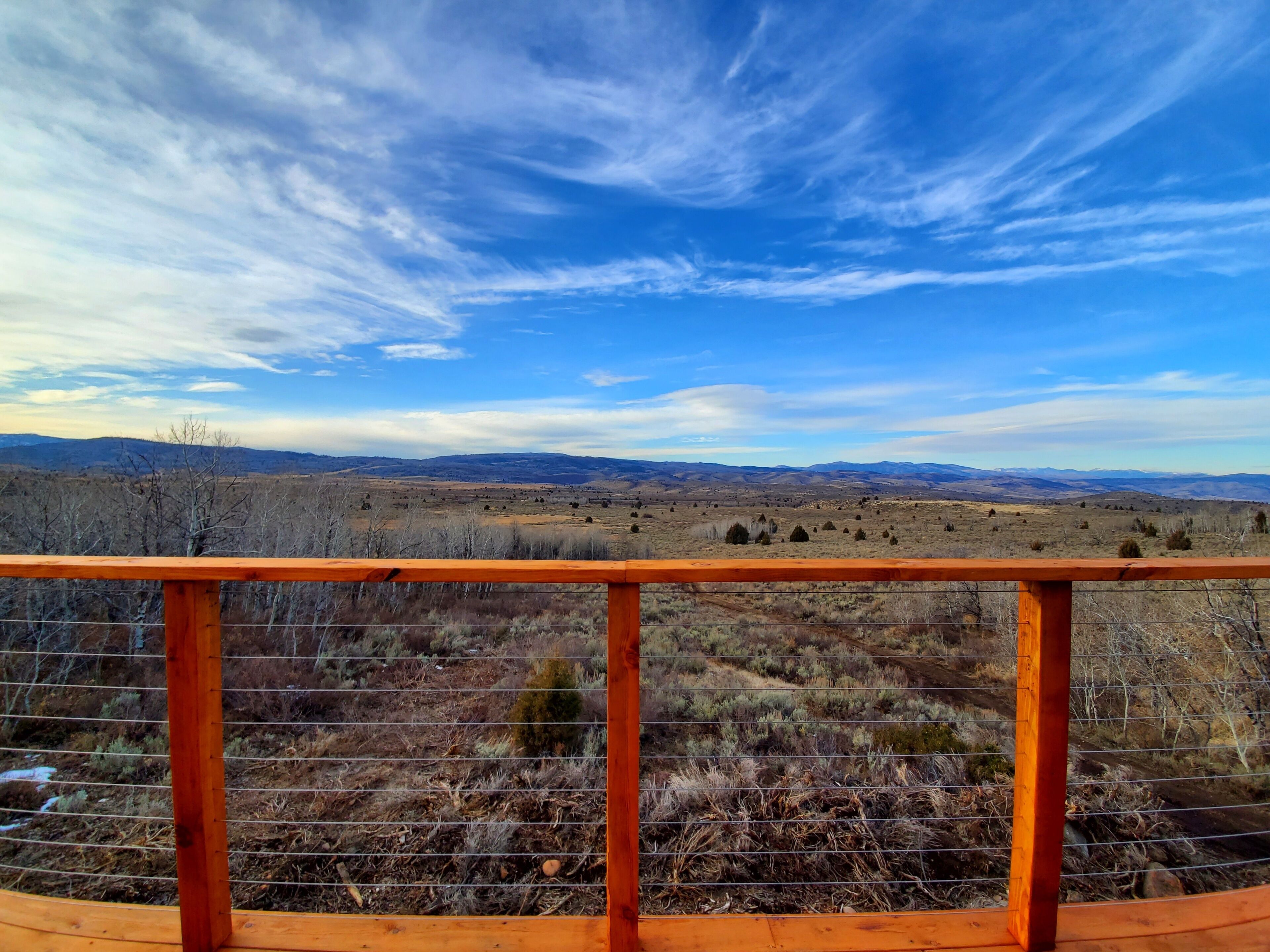 Une terrasse en bois offrant une vue sur un paysage montagneux.