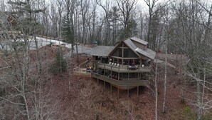 Uma cabana com terraço em vários níveis, rodeada por árvores e área arborizada.