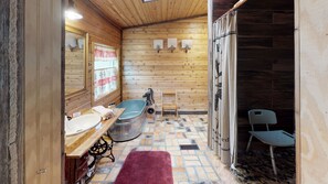 Een houten badkamer met een houten wastafel, een bad, een spiegel en een douchegordijn.
