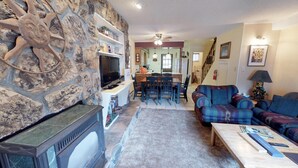 Ein Wohnzimmer mit Steinwand, Kamin, Fernseher und einem Essbereich mit Stühlen und Tisch.