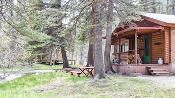 A rustic cabin with a porch, picnic tables, and a green door.