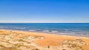 A beach with a clear sky, sandy shore, and a few vehicles parked along the beach. - Surf Crest Village #25 (Pelican Beach View) Ocean front 4 bedroom One pet only (ST. AUGUSTINE)