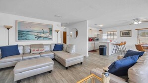 A modern living room with a sofa set, a dining area with a bar, and a kitchen. - Surf Crest Village #25 (Pelican Beach View) Ocean front 4 bedroom One pet only (ST. AUGUSTINE)