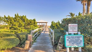 A wooden boardwalk leading to a gazebo, surrounded by lush greenery and palm trees. - Surf Crest Village #25 (Pelican Beach View) Ocean front 4 bedroom One pet only (ST. AUGUSTINE)