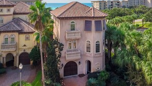A multi-story building with a terracotta roof, a central courtyard, and surrounding lush greenery.