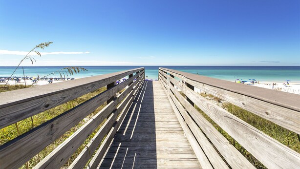 A wooden boardwalk leading to a beach with clear skies.