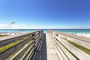 A wooden boardwalk leading to a beach with clear skies.