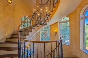 A grand spiral staircase with a wrought iron railing and a decorative chandelier.