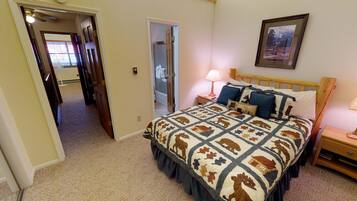 A bedroom with a bed, bedside table, lamp, and a framed picture on the wall.