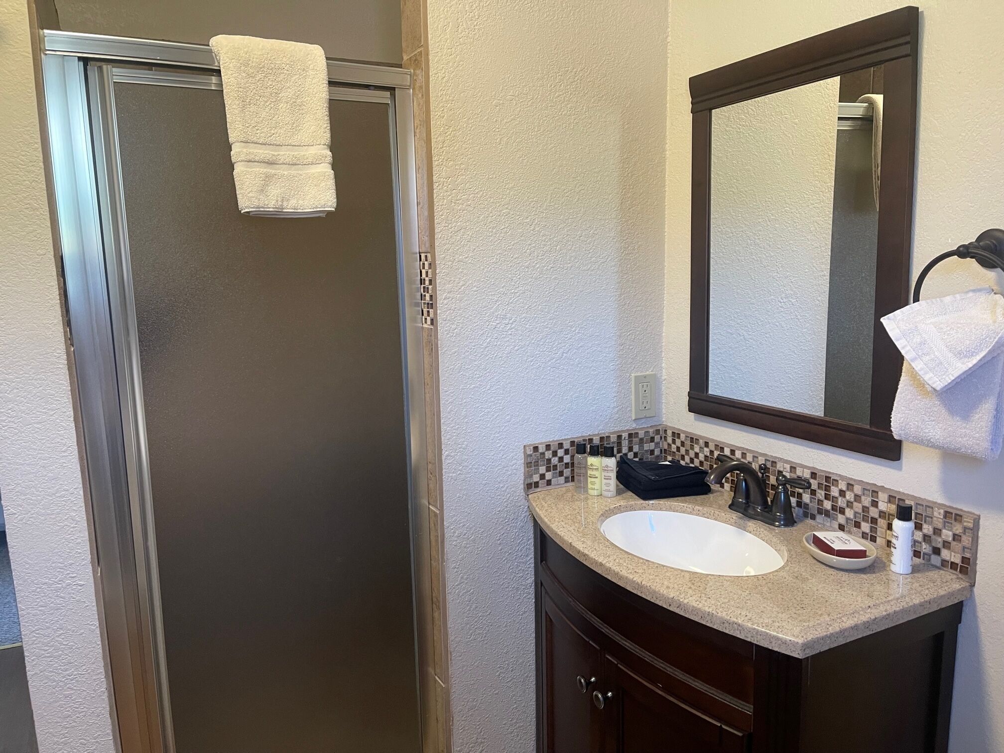 Une salle de bain équipée d’une douche, d’un lavabo, d’un miroir et d’articles de toilette.