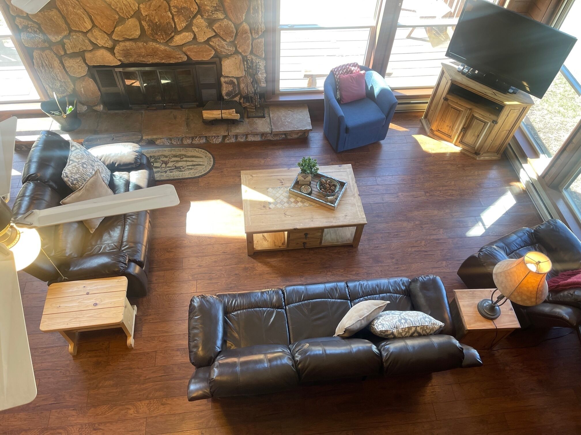 A cozy living room with a stone fireplace, leather sofas, a wooden coffee table, and a television.