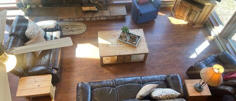 A cozy living room with a stone fireplace, leather sofas, a wooden coffee table, and a television.