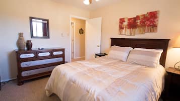 Une chambre à coucher avec un grand lit, une commode, un miroir et un tableau accroché au mur.