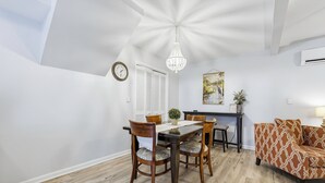 Un comedor con una mesa y sillas de madera, una lámpara de araña, un reloj y un cuadro en la pared.