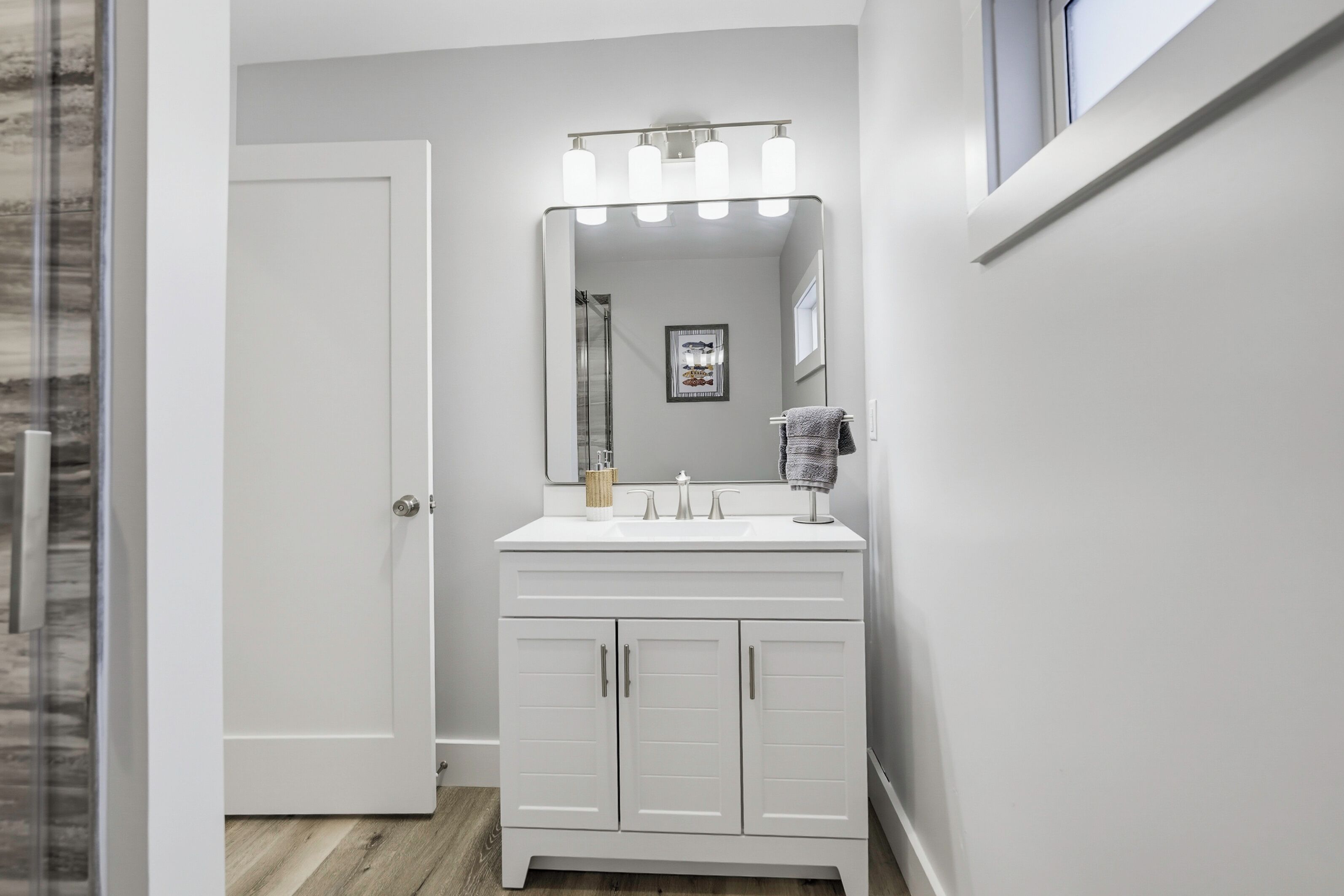 A bathroom with a white vanity, a large mirror, and a shower.