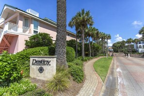A sign for 'Destiny' hotel with a paved pathway, palm trees, and a clear blue sky.