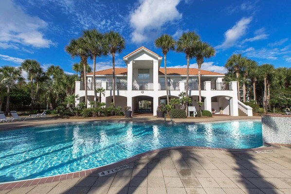 A large, white, two-story building with a swimming pool in front.