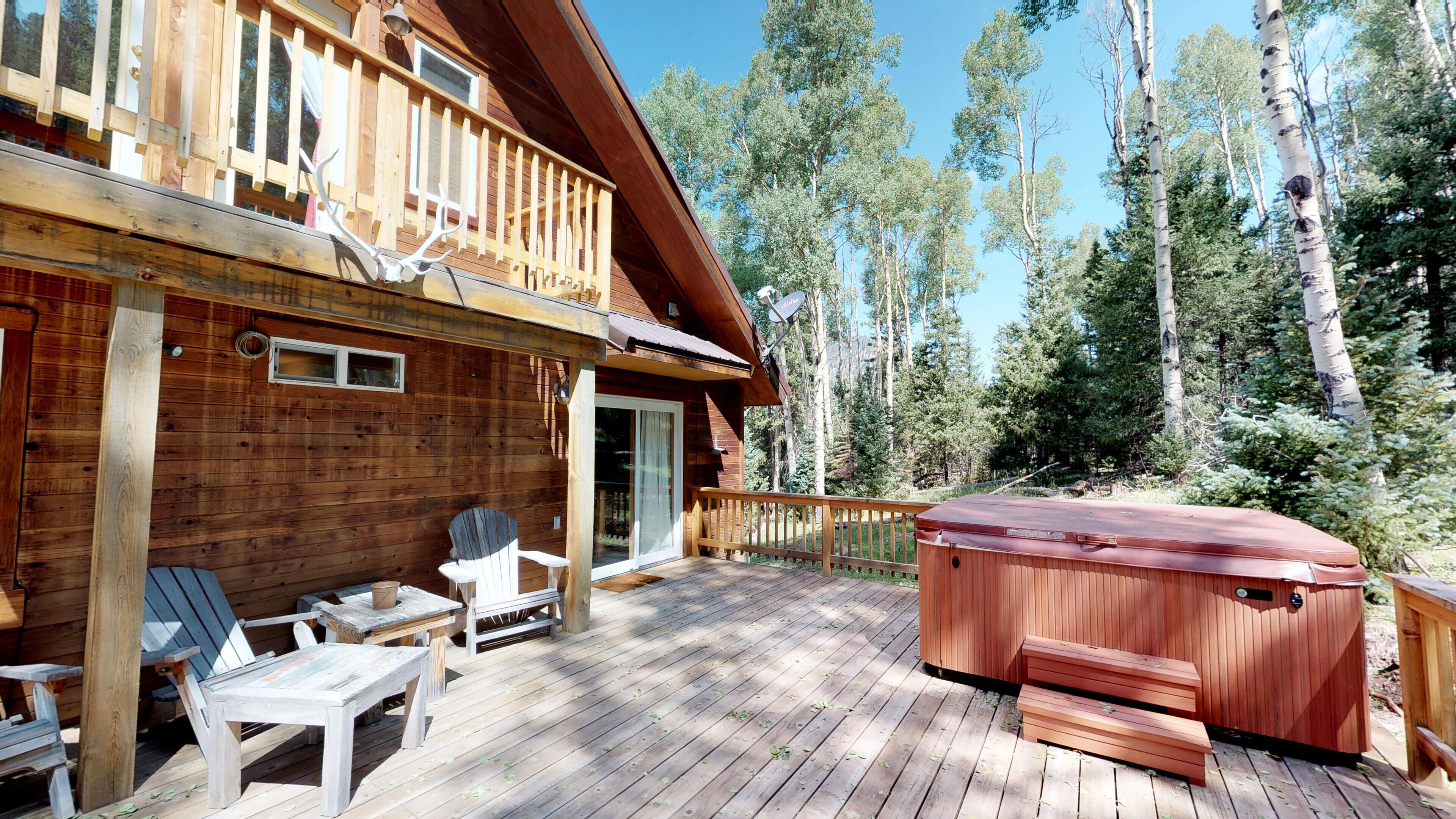 Una cabaña de madera con terraza, mobiliario exterior y jacuzzi.