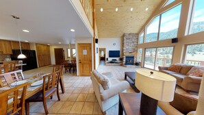 A spacious living area with a fireplace, large windows, and a dining area with wooden furniture. - 29 Valley of the Pines with Hot Tub in the Upper Valley (Red River)