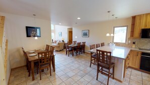 A spacious kitchen with wooden cabinets, a dining area with chairs, and a large island. - 29 Valley of the Pines with Hot Tub in the Upper Valley (Red River)