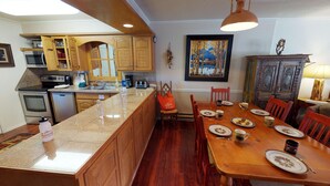 A kitchen with wooden cabinets, a granite countertop, and a dining area with a wooden table and chairs.