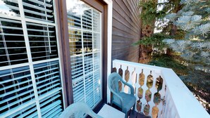 A balcony with a view of a building, a chair, and a decorative fence.