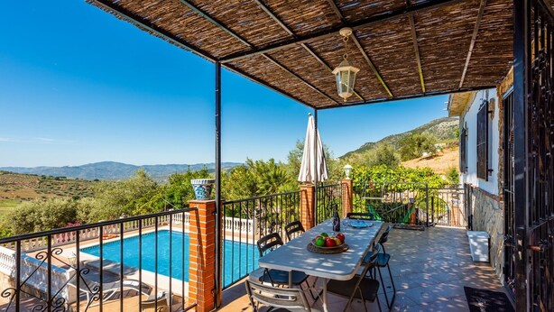 A covered outdoor area with a pool, a table with chairs, and a view of the countryside. - Villa Fablas Periana by Ruralidays (Málaga)