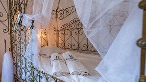 A bed with white linens and two towels with a logo, a wrought iron headboard, and a canopy. - Villa Fablas Periana by Ruralidays (Málaga)