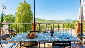 A terrace with a table set for two, a bottle of wine, and a bowl of fruit. - Villa Fablas Periana by Ruralidays (Málaga)
