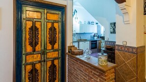 A kitchen with a rustic design, featuring a brick backsplash, a wooden door with intricate carvings, and a stone fireplace. - Villa Fablas Periana by Ruralidays (Málaga)