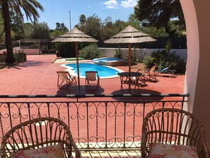 A pool area with two umbrellas, lounge chairs, and a small table.