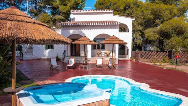 Un área de piscina con jacuzzi, muebles de exterior y sombrillas.